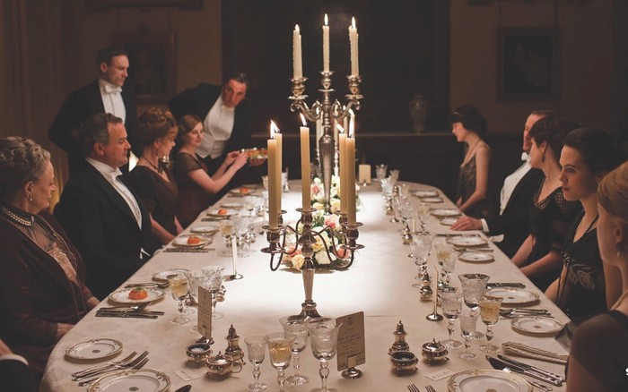 A dinner scene from Downton Abbey, with large candlesticks on the table