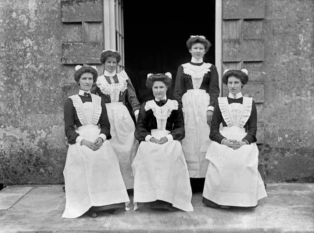 A black and white photo of five servants in Edwardian serving dress