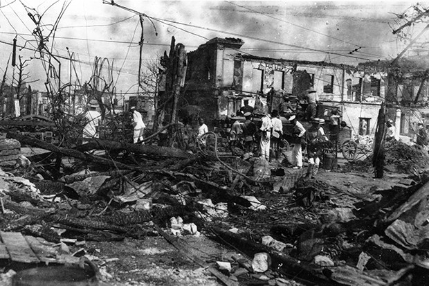 Workers operate among the charred remains and skeletal shells of buildings a month after the 1923 quake