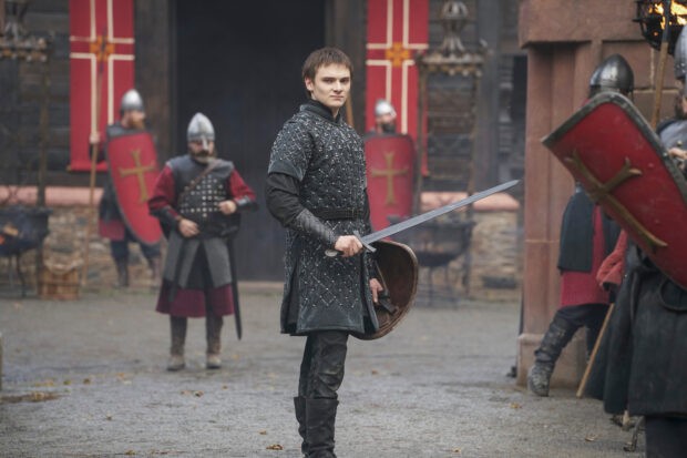Prince Edmund stand with in a training yard holding a sword and shield in Vikings Valhalla